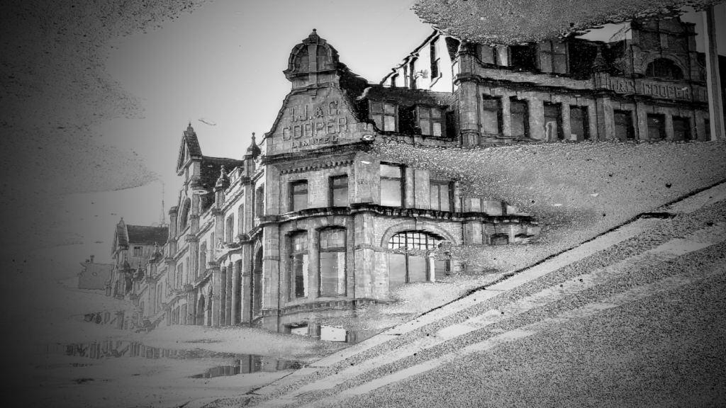 Black and white photograph of Victorian-era buildings on Lever Street in Manchester, showing ornate brick architecture with distinctive bay windows and decorative stonework against a cloudy sky.