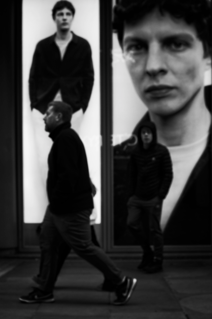 Black and white triptych-style photograph showing a person in dark clothing across three different panels or frames, with varying focus and perspectives creating an artistic portrait composition.