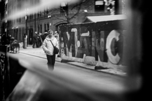 Black and white photograph of a reflection showing people and a railway car, with the center in sharp focus and deliberately defocused edges creating a tunnel vision effect.